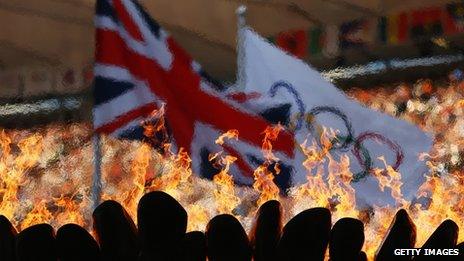 The Olympic Cauldron burns in front of the Union Jack and Olympic flag