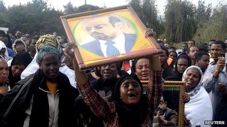 A woman wails while lifting a portrait of Ethiopia's Prime Minister Meles Zenawi as she waits for the arrival of his remains in Ethiopia's capital Addis Ababa, 21 August 2012