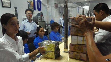 A branch of ACB bank in Vietnam's capital Hanoi shows staff transferring blocks of dong to customers on 23 August 2012