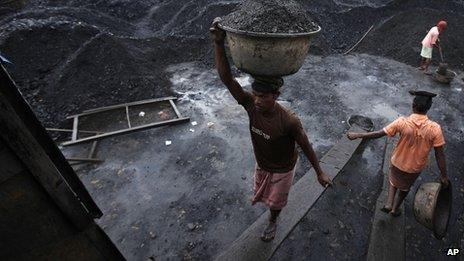 Workers load coal onto a truck at a coal depot in Gauhati, India,