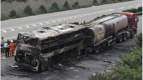 Police officers and rescuers inspect the wreckage of a bus and tanker in Yanan Aug 26