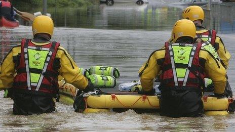 A fire rescue team with a dingy make their way down a flooded street