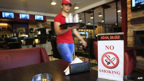 A waitress walks past a No Smoking sign in a cafe in Beirut on 3 September 2012