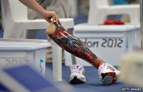 Swimmer's prosthetic leg is moved by official during swimming heat