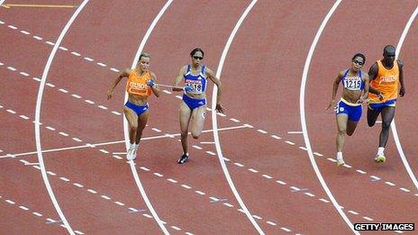 Blind athletes running round left-hand curve on race-track with guide runners