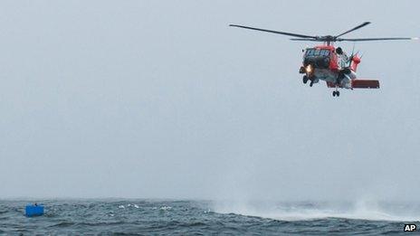 A photo taken from a nearby vessel shows the Coast Guard helicopter as it rescued Harris, below left