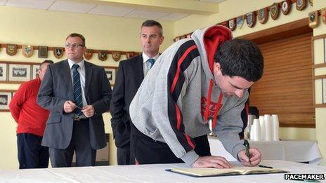 People signing condolence book