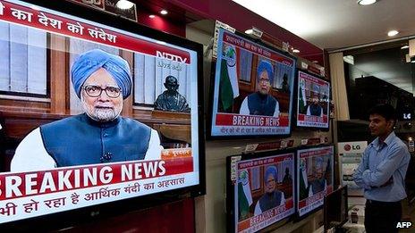 Salesmen in New Delhi, India watch Prime Minister Manmohan Singh address the country, 21 September 2012