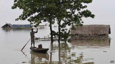 A man rows a country boat past partially submerged houses in Burhabrhi village about 65km (41 miles) east of Gauhati, Assam state, India, Monday, Sept. 24, 2012