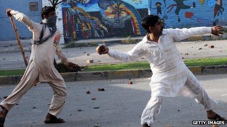 Pakistani Muslim demonstrators throw stones towards police during a protest against an anti-Islam film in Lahore on September 21, 2012