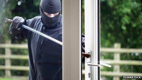 Man with crowbar breaking into a house