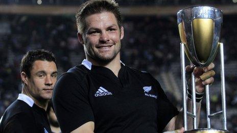 New Zealand captain Richie McCaw poses with the trophy in front of teammate Dan Carter