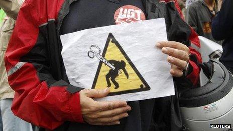 A public-sector worker holds a sign protesting against austerity cuts during a protest against Spain's 2013 cost-cutting budget, in Barcelona on 28 September 2012