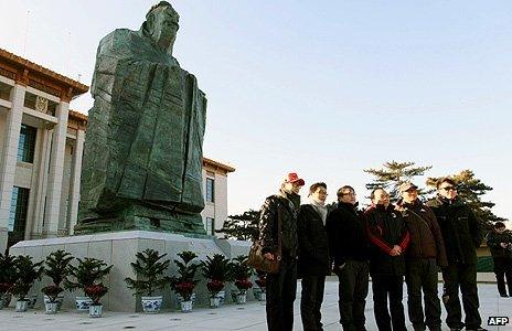 Chinese tourists pose in front of a statue of Confucius in Beijing's Tiananmen Square