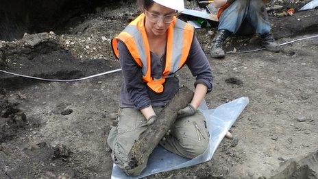 Archaeologist holding a wooden stake carved by humans to make a trackway across the marshland, allowing hunters to access the rich floodplain wildlife