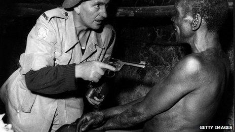 Mau Mau prisoner under guard in Kenya after a night raid organised by the British Army and the Kenya police to find members of the movement - November 1952