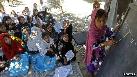 Pupils watching as girl writes on blackboard