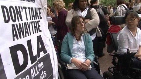 Protesters beside placard defending the disability living allowance