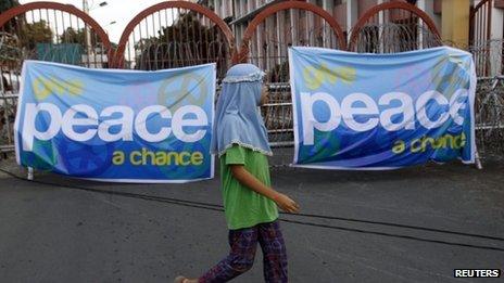 A Muslim girl walking past a banner showing support for the signing of the peace deal between the government and MILF rebels in Manila, 14 October 2012