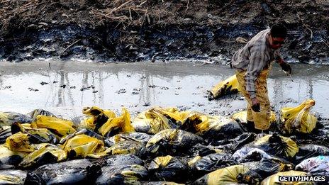 A Chinese worker cleans up a stream which has been polluted after an oil pipeline to a factory burst, in Beijing on March 28, 2012.