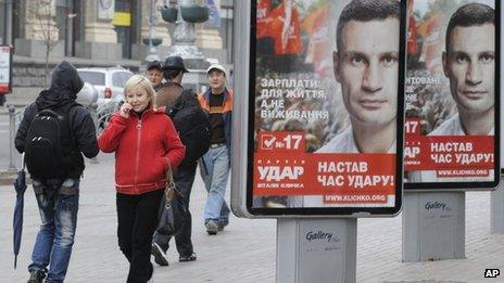 People walk past election posters of Ukrainian boxer and Chairman of the Ukrainian Udar Party, Vitali Klitschko in Kiev, Ukraine, Thursday, Oct. 18, 2012.