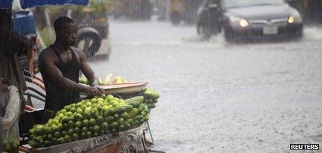 A man arranges fruits in a wheelbarrow along a flooded street in Lagos, 8 October 2012