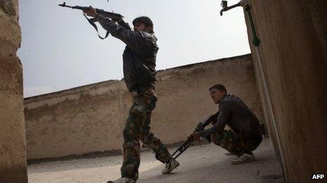 Rebel fighters fire from the rooftop of house against Syrian government forces in the Bab el-Adid district in Aleppo on 23 October 2012