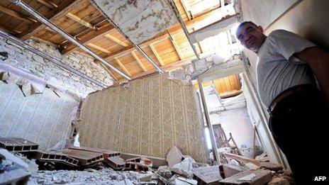 L'Aquila resident stands in their devastated house