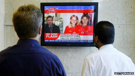 Two men watch breaking news about the Soham murders