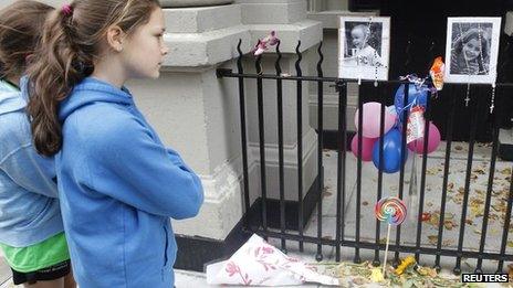 A young girl looks at a makeshift memorial left outside the Krim family apartment in New York