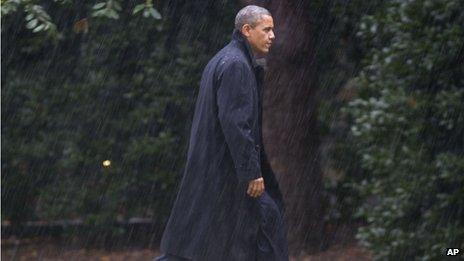 After cancelling a rally, President Obama walks through the driving rain