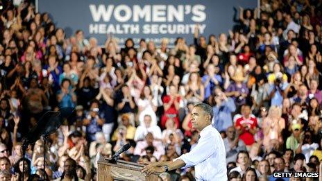 Obama at a campaign rally in Denver in August 2012, with a big banner saying "women's health security"