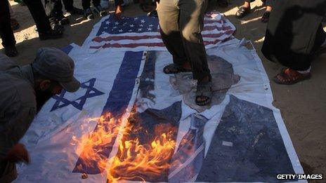 Palestinian Salafists walk on top of a picture of US President Barack Obama while burning Israeli and US flags