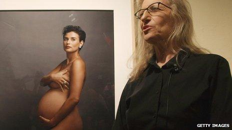 Photographer Annie Leibovitz stands in front of a portrait of pregnant actress Demi Moore