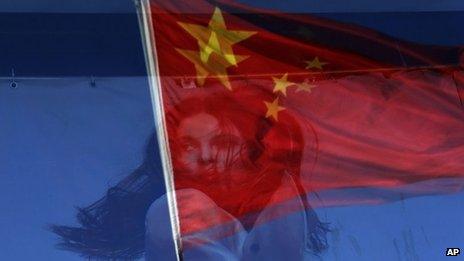 The Chinese flag is reflected on a fashion poster at a shopping mall in Beijing, China, 12 November 2012