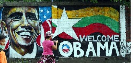 A woman takes a photo of a wall painting created by Burmese graffiti artists to welcome President Barack Obama in Rangoon