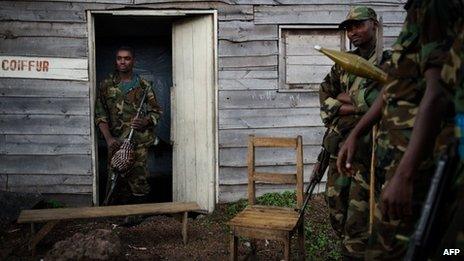 M23 rebels stand outside a small wooden shack in the village of Kanyarucinya, 6km from Goma, in eastern DR Congo, 18 November 2012