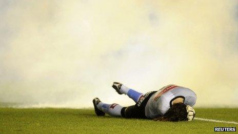 Goalkeeper Juan Carlos Olave from Argentine soccer club Belgrano lies on the pitch after being hit by a flare in a match against Independiente