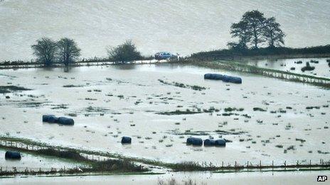 A vehicle manages to drive along a road between flooded land in Somerset