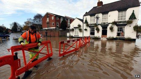 A highways agency worker barriers off the road outside the White Bear Pub in Tewkesbury to stop motorists driving through flood water and flooding the pub further