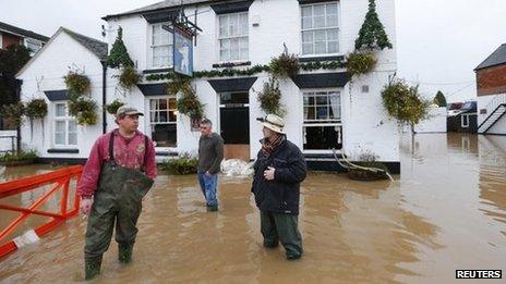 People stand in flood water outside the White Bear pub in Tewkesbury