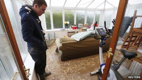 James Evans looks at muddy sediment left after water receded from his home in St Asaph