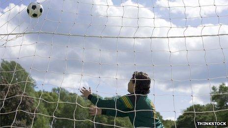 Young goalkeeper struggles to reach to save a shot