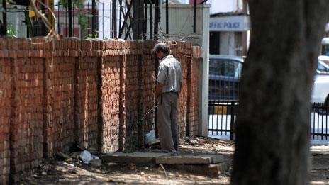 Man urinating against wall