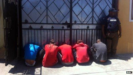 A policeman stands over four arrested gang members