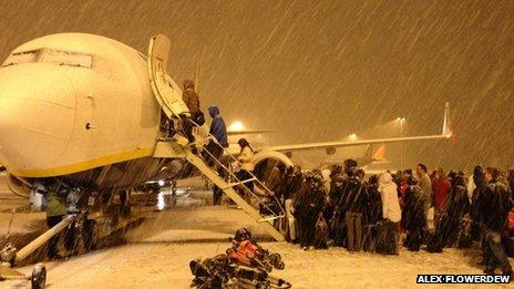 Passengers boarding aircraft in heavy snow