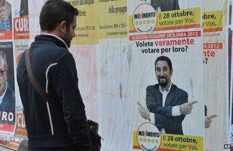 A man looks at a Five Star Movement poster during a local election campaign in Sicily, 28 October