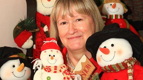 Diana Howes sits on the stairs with part of her collection of snowmen