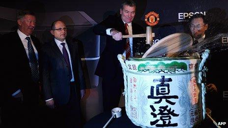 Alex Ferguson grins as Man Utd chairman David Gill spills the sake, to mark a deal on a new sponsorship deal with Epson