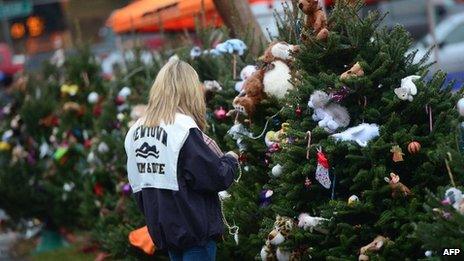 A teenager decorates Christmas trees set up at a makeshift shrine to the victims of a elementary school shooting in Newtown, Connecticut, 16 December 2012